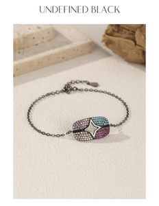 Detail of black punk bracelet with pink and blue stones on beige stone background