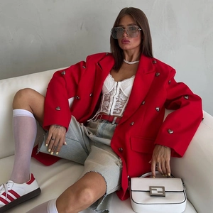 Detail of red blazer jacket featuring heart-shaped metal button and sharp lapel design
