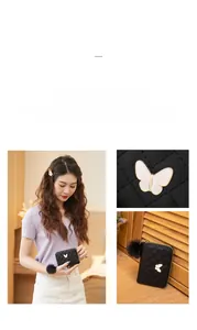 Detail of black quilted leather purse with white butterfly charm and fluffy pompom