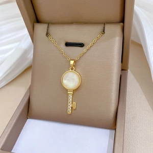 Detail of gold key necklace with mother of pearl inlay and micro-pave zircons in a box