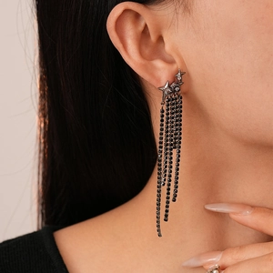 Close-up of black star tassel earrings with rhinestones worn by a model in profile