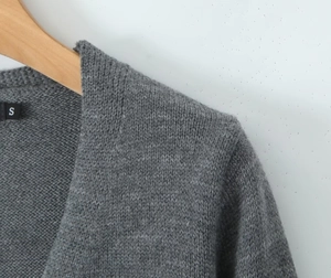 Détail du pull en maille grise présentant un col en V et une étiquette de taille S