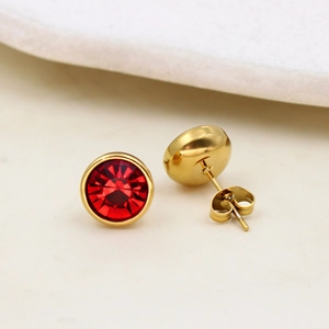 Macro detail of gold round stud earrings featuring faceted red crystal inlays