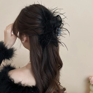 Detail of elegant black feather hair claw clip on long wavy hair with tulle accents