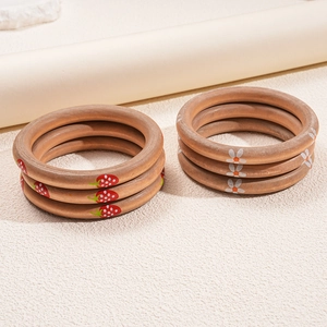 Three-piece wooden bangle set with strawberry and daisy floral prints in a warm natural finish