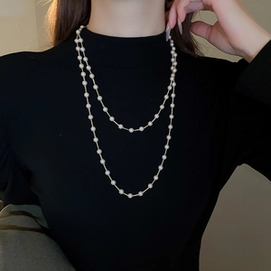Gros plan d'un élégant collier de perles à double rang sur un pull à col roulé noir