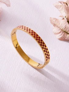 Detail view of gold checkered enamel hinge bangle with elegant red and gold patterns