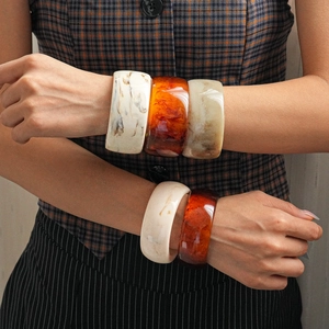 Detail showing thick wide marble texture resin bangles in amber and ivory colors