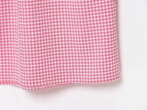 Détail de l'ourlet de la robe vichy rose et blanc avec texture de couture de qualité