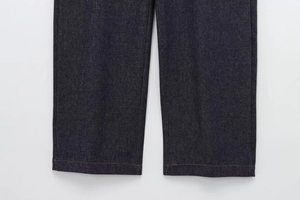 Close-up of denim pants hem featuring precise contrast stitching on dark navy fabric