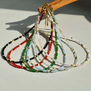Detail of colorful faceted crystal beaded necklaces with gold spacers on wooden stand