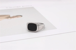Gros plan d'une chevalière en argent avec incrustation carrée noire sur fond blanc
