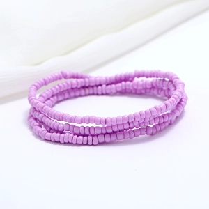 Macro detail of double-layer purple seed bead waist chain on soft white silk fabric