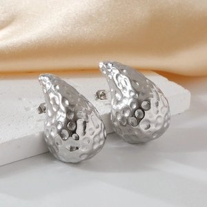 Elegant silver teardrop earrings with hammered texture on a silk and stone background