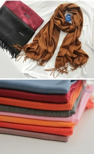Close-up of stacked colorful cashmere scarves with tassels in multiple classic solid shades