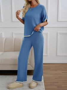 Detail of blue knit set featuring short sleeve top and trousers with cream piping