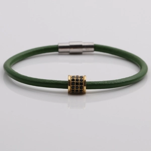 Fashionable green woven leather bracelet with gold cylinder charm and magnetic clasp