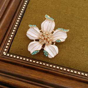 Détail d'une broche fleur vintage avec émail blanc et bordure en perles turquoise