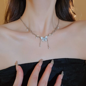 Dettaglio della collana a farfalla d'argento con nappe di cristallo e perle sul collo