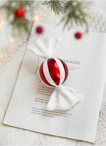 Detail of red and white striped Christmas candy ornament with glitter on a white background