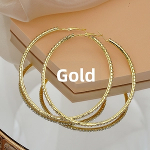 Macro shot of large gold-tone hoop earrings with glittering rhinestones on a display