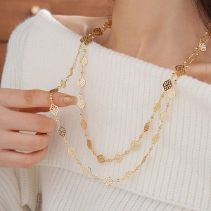Detail of vintage hollowed rhombus gold necklace on a white knitted sweater