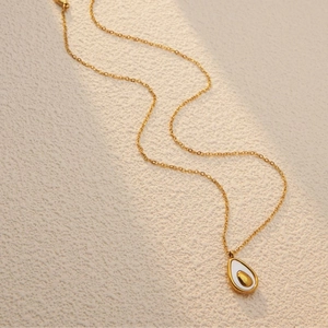 Elegant gold chain necklace with avocado teardrop pendant on minimalist background