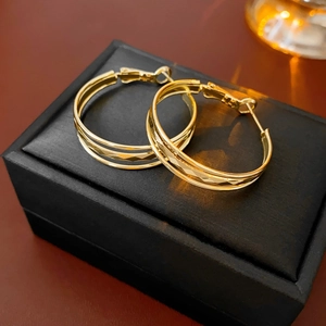 Nahaufnahme von mehrlagigen goldenen Creolen mit Facettenschliff auf einer Schmuckbox
