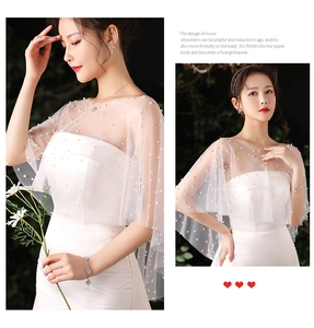 Detail of white bridal tulle shawl with scattered pearls and loose shoulder design