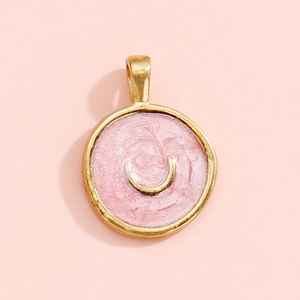 Detail of round gold pendant with pink enamel finish and golden crescent moon design