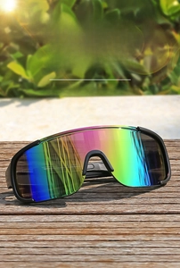 Close-up of oversized sports goggles with rainbow mirrored lenses on wooden surface