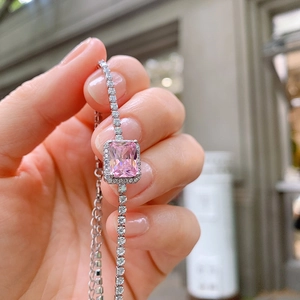 Close-up of elegant silver tennis bracelet with halo-set rectangular pink zircon stone