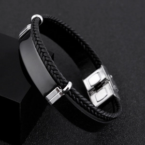 Close-up of men's braided leather bracelet with stainless steel plate and clasp details