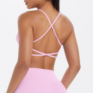 Détail des bretelles croisées dans le dos d'un soutien-gorge de sport rose pâle de yoga