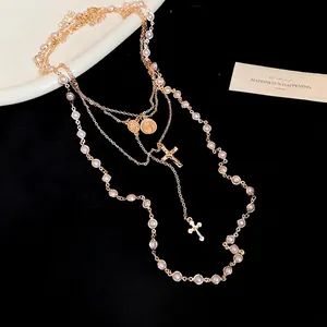 Layered gold necklace featuring pearl strands, cross pendants and vintage coin charms