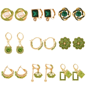 Set di 9 paia di orecchini vintage in oro con gemme verdi e perle su sfondo bianco