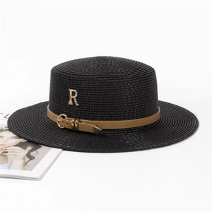 Détail d'un chapeau de paille noir avec ceinture en cuir marron et lettre R dorée
