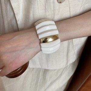 Close-up of wide acrylic marbled bracelet with ivory resin and gold metal modules