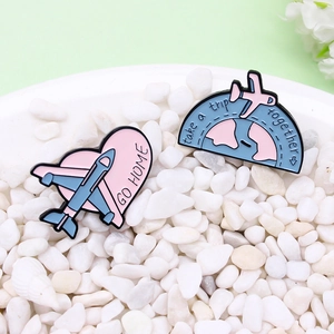 Creative airplane travel enamel pins with heart and globe motifs on white stones