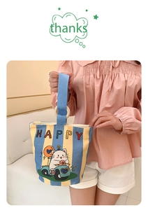 Detail of canvas bucket bag with cat illustration, wooden rings and blue striped pattern