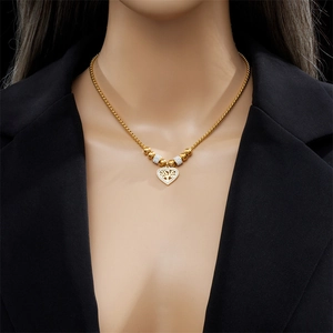 Golden heart tree of life pendant necklace with beaded chain worn by a female model