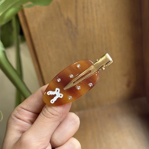 Amber acetate hair clip with rhinestones and gold alloy clasp held by hand