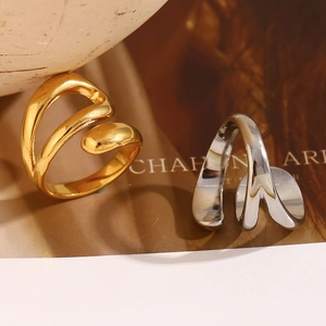 Artistic close-up of gold and silver irregular triple-layer snake rings on a neutral backdrop