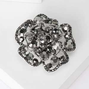 Detailed macro view of 3D rose brooch featuring dark grey crystals and metal petals