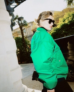 Detail view of bright green oversized jacket with sleeve pocket and sleek crossbody bag