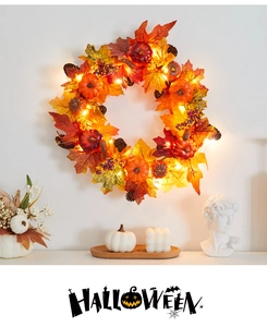 Detail of lit Halloween garland with pumpkins, maple leaves, and berries on a wall