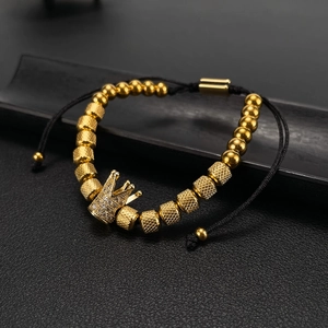 Gold crown bead bracelet with rhinestones and black woven rope on dark display