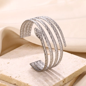 Detailed macro view of silver snake-scale textured multi-layer spiral arm cuff on stone