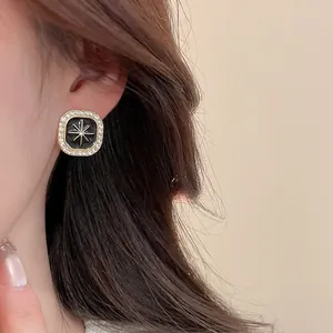 Detailed close-up of retro square earrings featuring black enamel and starburst crystals