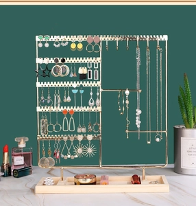 Detail of a 5-tier gold metal jewelry organizer with a natural wooden base tray